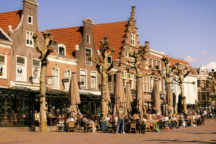 Het terras van Café de Roemer onder parasols voor de historische trapgevels aan de Botermarkt in Haarlem.