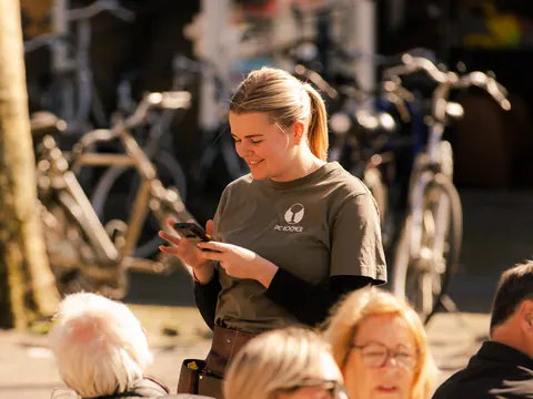 Medewerker van Café de Roemer neemt op het terras een bestelling op met een handterminal.