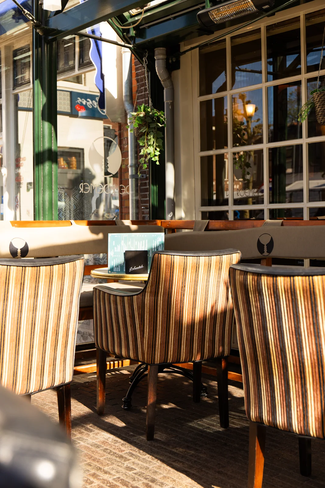 Gestreepte stoelen en ronde tafels langs het raam van de serre.